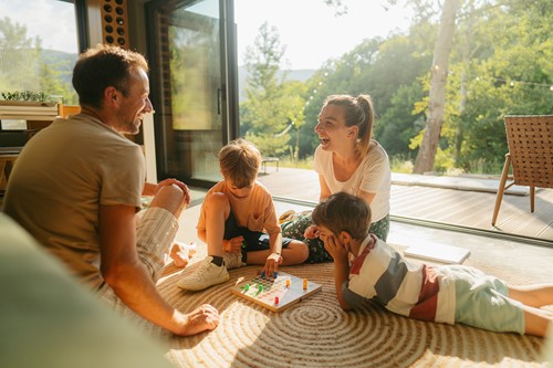 A family of four with two children having a good time together playing games in their home.