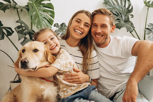 A family of three together with their dog in their home.